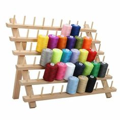 several spools of thread are on a wooden rack with two rows of spools