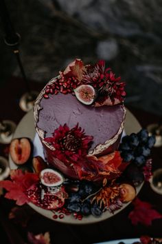 a cake with fruit and flowers on it sitting on a table next to other food