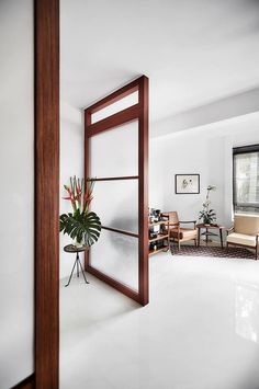 an open door leading to a living room with chairs and a plant in the corner