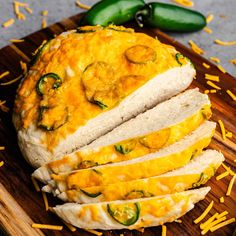 sliced bread with cheese and jalapenos on a cutting board next to green peppers