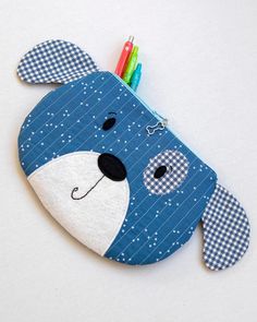 a blue and white stuffed animal with pens in it's mouth