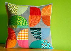 a colorful pillow sitting on top of a wooden table next to a green painted wall