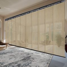 a living room with a large rug and beige curtains on the windowsills that are open