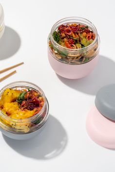 two glass containers filled with food next to chopsticks