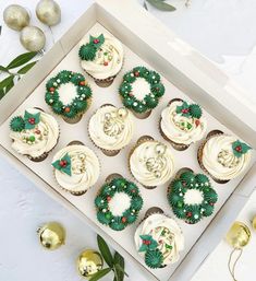 cupcakes decorated with green and white frosting in a box next to christmas decorations