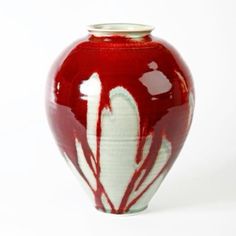 a red and white vase sitting on top of a table