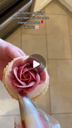 a person is holding a cupcake with a rose on it