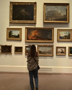 a woman is looking at paintings on the wall