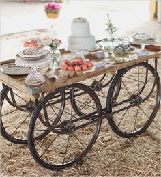 a table that has some cakes on it and plates in front of it with flowers hanging from the ceiling