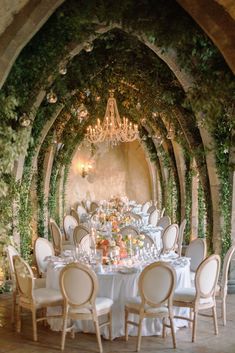 an image of a table set up for a formal dinner with chandeliers and greenery