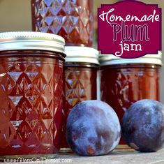 jars filled with plum jam sitting on top of a table