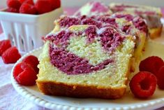 slices of raspberry swirl cake on a white plate with raspberries in the background