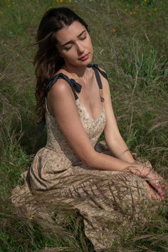 a woman sitting in the grass with her eyes closed