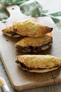 three pastries sitting on top of a wooden cutting board