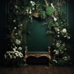 a green wall with white flowers and greenery on it, next to a gold bench