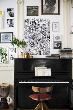 a black piano sitting in the middle of a room with pictures on the wall above it