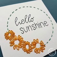 an embroidered card with the words hello sunshine written in black and orange on white paper