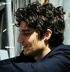 a man with curly hair looking at his cell phone