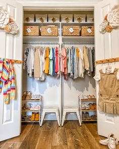 an organized closet with clothes and shoes hanging on the wall, along with baby's clothing