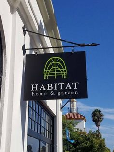 a sign hanging from the side of a building that says habitat home and garden on it