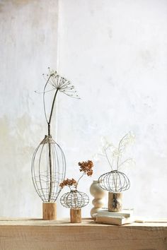 three wire vases with flowers in them on a table