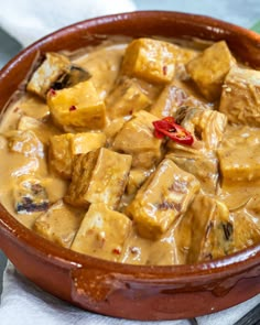 a brown bowl filled with tofu and sauce