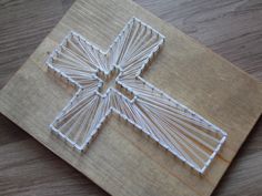 a cross made out of string sitting on top of a wooden table next to a pair of scissors