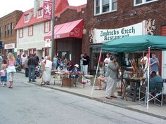 people are walking down the street in front of shops and businesses with green awnings