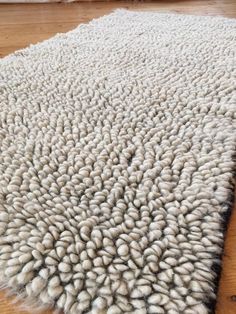 a large white rug on top of a wooden floor