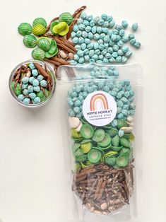 two bags filled with green and blue candies next to a bowl of candy beans