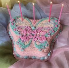 a heart shaped cake with candles in the shape of a butterfly