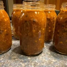 four jars filled with food sitting on top of a counter