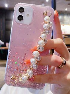 a woman holding up her phone case with pearls on it