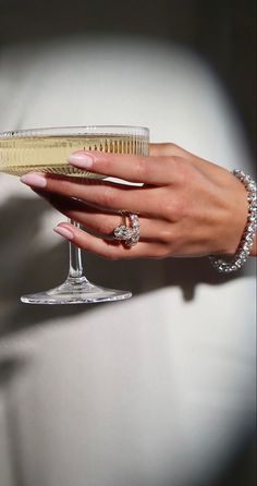 a woman's hand holding a champagne glass with a diamond ring on it,