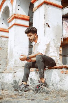 a man sitting on top of a wooden bench in front of a white and orange building