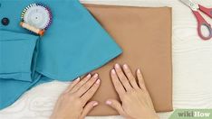 two hands on top of a brown cloth next to scissors and other crafting supplies