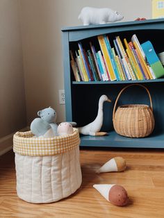 a bookshelf filled with lots of books next to a basket and stuffed animals