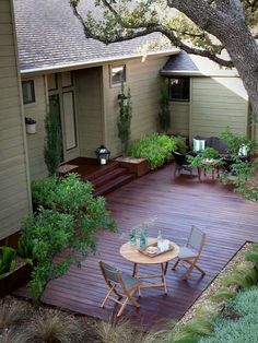 a wooden deck in the middle of a yard with chairs and table on top of it