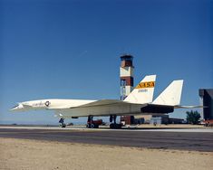 an airplane is parked on the runway in front of a control tower