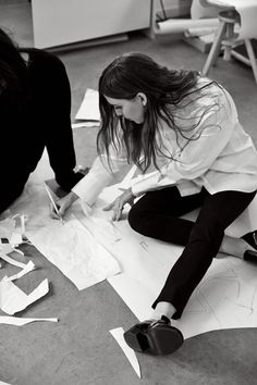 two women sitting on the floor working on paper