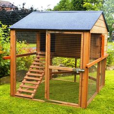 a small chicken coop with stairs to the top and side door open on green grass