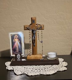 a wooden cross sitting on top of a table next to a cup and saucer