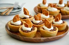 several small desserts on wooden plates with white frosting and toppings are sitting on a table