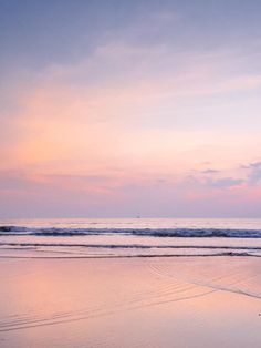 two people walking on the beach at sunset