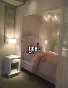 a white bed sitting under a chandelier next to a night stand and table