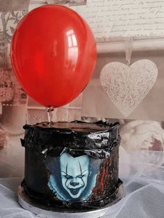 a cake with a clown face on it and a red balloon attached to the top