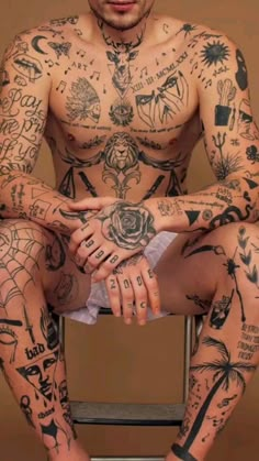 a man with lots of tattoos sitting on top of a chair