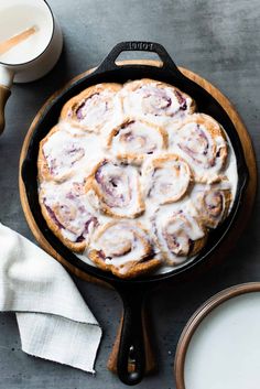 a cinnamon roll in a cast iron skillet next to some milk and other ingredients