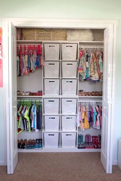 an organized closet with baskets and clothes hanging on the wall next to shelves filled with children's clothing