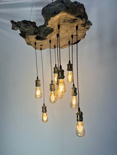 several light bulbs are hanging from a wooden beam with chains attached to it and suspended on a white wall